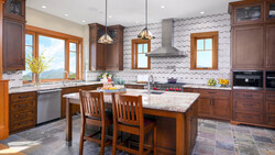 Bright kitchen interior with wood cabinetry, marble island, and geometric tile backsplash.