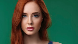 Woman with long reddish-brown hair and blue eyes against a solid green background.