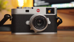 Leica M camera with silver and black body, Ultron lens, sitting on wooden surface with warm lighting.
