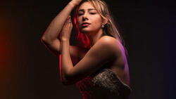 Woman posed against dark background with red and purple gel lighting.