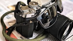 Vintage rangefinder camera with interchangeable lens on printed newspaper surface.
