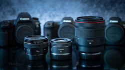 Canon EF 50mm prime lenses arranged in front of Canon DSLR camera bodies against a textured blue background.