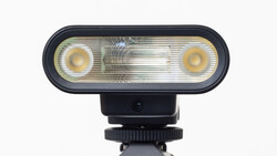 Camera-mounted flash unit with dual circular reflectors and central diffusion panel on hot shoe mount.