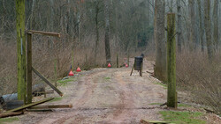 Outdoor training course with wooden obstacles and safety cones in bare winter forest.