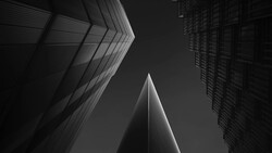 Three modern skyscrapers shot from below against dark sky, converging upward with sharp geometric lines.