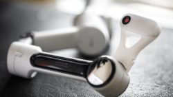 White wireless earbuds with charging case displayed on textured gray surface.