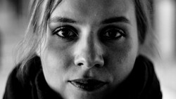 Black and white portrait of a woman with direct gaze and serious expression.