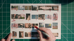 Contact sheet of architectural and landscape photographs laid flat on a cutting mat with hands marking selections in red.