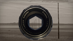 Vintage camera lens framing a row of utility poles stretching across a flat, desolate landscape under overcast sky.