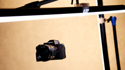 Sony mirrorless camera positioned on a cream-colored photography backdrop with studio lighting setup visible above.