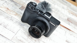 Canon EOS M6 Mark II compact camera with attached microphone on whitewashed wooden surface.