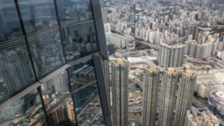 Aerial view from a high-rise window showing dense urban cityscape with numerous residential towers and construction sites below.