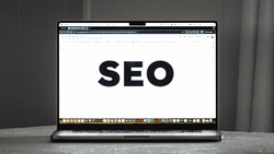 Laptop screen displaying the word 'SEO' in large black text on a white background.