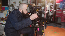 Photographer using a large format camera on a tripod in a workshop studio.