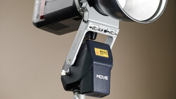 Flash unit with white bracket mounted on light stand against neutral background.