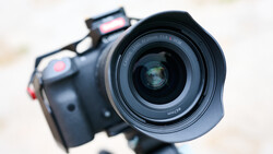 Close-up of a mirrorless camera with wide-angle lens mounted on a tripod, shot from the front.