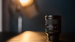 Camera lens on textured surface with warm bokeh lighting in background.