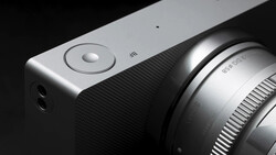 Close-up of a mirrorless camera body with attached lens against black background.