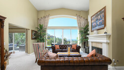 Luxury living room with high arched windows, tufted leather seating, and fireplace mantel.