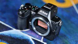 Nikon Z mirrorless camera body with open battery compartment displayed on colorful blue and yellow surface.