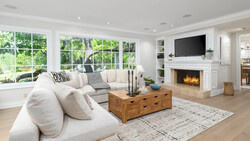 Modern living room with cream sectional sofa, wooden coffee table, and fireplace with mounted TV.