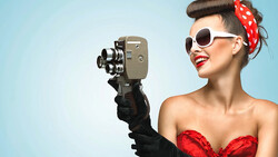 Woman in vintage-style outfit holding a film camera up to her face.