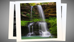 Multi-tiered waterfall cascading into an emerald pool surrounded by moss-covered rocks and lush green vegetation.