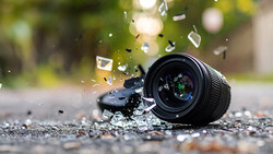 DSLR camera lying on pavement with water splashing around it.