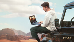 Man sitting on truck tailgate editing photos on laptop with desert landscape in background.
