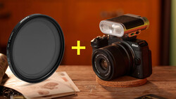 Nikon DSLR camera with external flash and circular neutral density filter arranged on wooden surface.