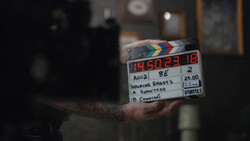Film production clapperboard held in hand with timecode and scene notes visible.