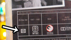 Close-up of DVD packaging showing CC and NTSC logos with an arrow pointing to the Closed Captioning symbol.