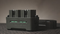Black battery charger with four AA or AAA slots and a green LED indicator light on the front panel.
