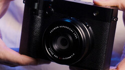Fujifilm X-Pro1 camera with Fujinon Aspherical lens held in hands during product demonstration.