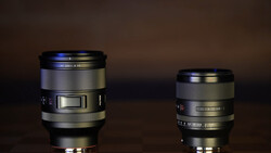 Two camera lenses of different sizes displayed side by side against a dark brown background.