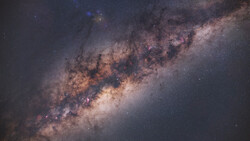 The Milky Way galaxy stretches diagonally across a dark night sky, showing the bright galactic core with dust lanes and nebulae.