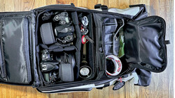 Professional camera backpack with organized gear compartments containing cameras, lenses, and photography accessories.