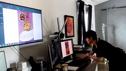 Photographer working at desk with multiple monitors displaying food photography and editing software.