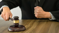 Judge striking wooden gavel on sound block during court proceeding.