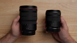 Two camera lenses held in hands side by side for comparison, showing different sizes and focal length ranges.