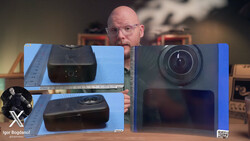 Tech reviewer comparing two compact camera models displayed on blue foam board against studio backdrop.