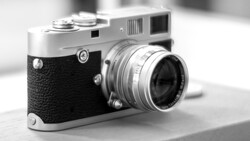 Vintage rangefinder camera with black leather grip and chrome top plate, fitted with a standard prime lens.