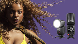 Portrait of woman with curled hair against purple background, with two external camera flashes displayed on right side.