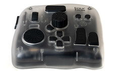 Transparent game controller with black buttons and analog sticks, displayed against white background.