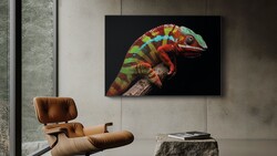 Photograph of a vibrant rainbow chameleon mounted on a branch, displayed on a black wall above a leather lounge chair.