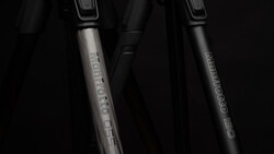 Two bicycle fork shock absorbers with text engravings on metallic stems against a dark background.