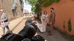 Wedding photography session in an urban alley with a photographer using a telephoto lens in the foreground.