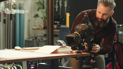 Photographer adjusting a cinema camera mounted on a tripod in a studio setting.