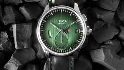 Leica chronograph watch with green dial and black leather strap on textured stone background.