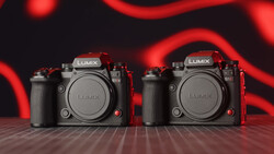 Two Panasonic Lumix mirrorless cameras positioned side-by-side against a dark background with red neon lighting.